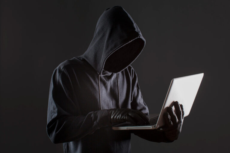 hacker w rękawiczkach z laptopem
